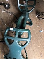 Full view of green two-seat glider swing showing seats, center beam and attached chains