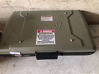 Closed Coleman portable grill showing lid, handle, warning labels