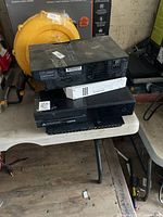 Stack of four consoles: PS2, Wii, Xbox One, PS4 on table