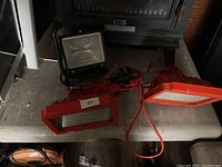 Top view of two red work light housings and one black floodlight on table
