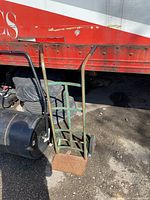 Full view of green steel hand truck with solid wheels and rusted toe plate