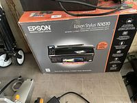 Retail box showing Epson Stylus NX510 printer, features listed