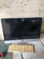 Front view of Apple iMac showing broken screen and beige keyboard with missing keys