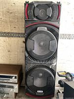 Front view of entire tower speaker showing driver layout and red trim.