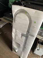 Front view of faucet in foam packaging showing arched spout and handle