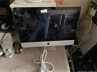 Front view of Apple iMac showing cracked screen and attached power cord