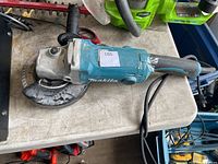 Top view of Makita corded angle grinder showing body, guard, handle and cord
