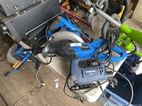 All three corded power tools on table: blue circular saw, black reciprocating saw, blue jigsaw