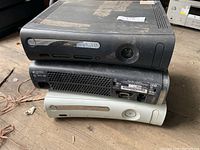 Stack of three Xbox 360 consoles showing front and rear, two black, one white