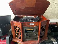 Overall view of wooden stereo turntable with lid open showing record on platter and front control panel