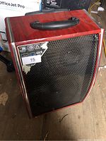Front of red portable PA speaker showing metal grille, control panel, peeling veneer