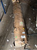 Long cardboard box containing disassembled bed frame components