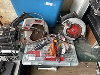 Two corded circular saws, Milwaukee bit kit, hand tools on table