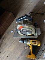 Makita corded circular saw and DeWalt cordless hammer drill on wooden floor