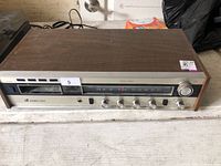 Front view of vintage stereo receiver showing tuner, 8-track slot, controls and wood case