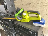 Left side view of Sun Joe cordless hedge trimmer resting on electronics stack