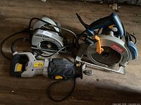 Three corded saws on wooden floor: two circular, one reciprocating