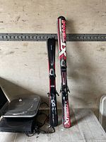 Both pairs of skis leaning against wall