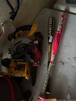 Both softball bats on table, Easton black-gold and pink multi-color bats visible