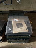 Yorx stereo stack with dust-covered turntable and manual on lid, Toshiba unit edge visible