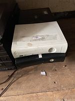 White and black Microsoft Xbox 360 consoles stacked on surface