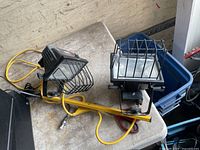 Two halogen work lights with wire guards and cords on tabletop