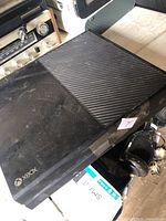 Top angled view of black Xbox One console showing exterior condition and crack in housing