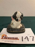Front view of Hubley cast iron puppy bank on pillow with bee motif and lot card