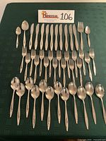 Full view of 42-piece Oneida Lasting Rose flatware laid out in rows