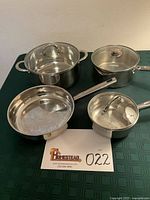 All four stainless steel cookware pieces with lids displayed together