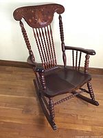 Front full view of the antique spindle back rocking chair showing overall design and condition.