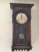 Full view of the antique wooden wall clock mounted on the wall.