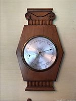 Full view of vintage wooden barometer with hexagonal shape and carved top and bottom details.