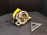 Photo showing DeWalt circular saw and metal speed square together on black surface.