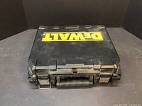 Closed black hard plastic case with yellow DeWalt logo on top, showing metal latches and handle.