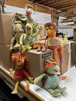 Seven Fraggle Rock plush dolls and two Dozer toys arranged on boxes