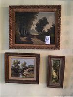 Three framed pastoral paintings hung on wall, large horizontal on top, medium square and small vertical below