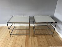 Pair of chrome and glass square tables side-by-side showing overall appearance and dimensions relative to floor
