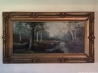 Full view of the framed landscape canvas painting in gold ornate frame.