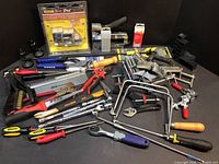 Wide view photo showing the assortment of miscellaneous hand tools including screwdrivers, saws, clamps, wrenches, and boxed items.