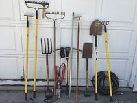 Photo showing a variety of yard tools including rakes, shovels, a pitchfork, a garden hose and the Black and Decker Alligator pruning shear in the middle.