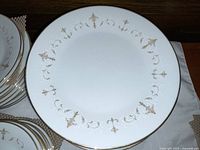 Close-up photo of white Noritake Courtney dinner plate with gold detailing along the rim.