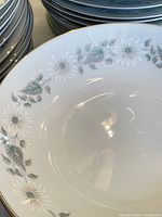 Close-up of the floral pattern on a Noritake Wellesley plate showing white flowers and blue-gray leaves on white porcelain.