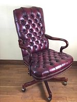 Full view of chair showing tufted high back, seat cushion, wood scroll arms and swivel base