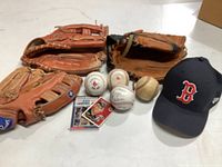 Overview photo of all items showing gloves, baseballs, baseball cards and cap.