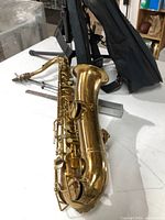 Overview of saxophone on table with stands and case behind