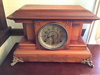 Full front view of the vintage Seth Thomas Adamantine mantle clock with wood case and decorative metal feet.