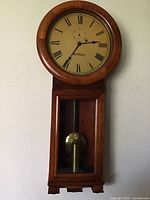 Straight-on view of clock mounted on wall showing full dial, bezel and lower case
