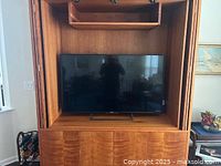 55" TV installed in wooden cabinet, shows front view and stand