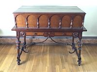 Full frontal view of desk with front panel closed, showing carved arches and turned legs.